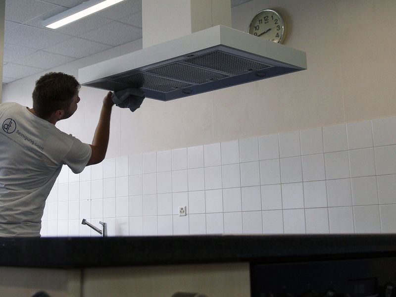 Mitarbeiter der DT Reinigung GmbH reinigt eine Lüftungsabdeckung in einer Küche